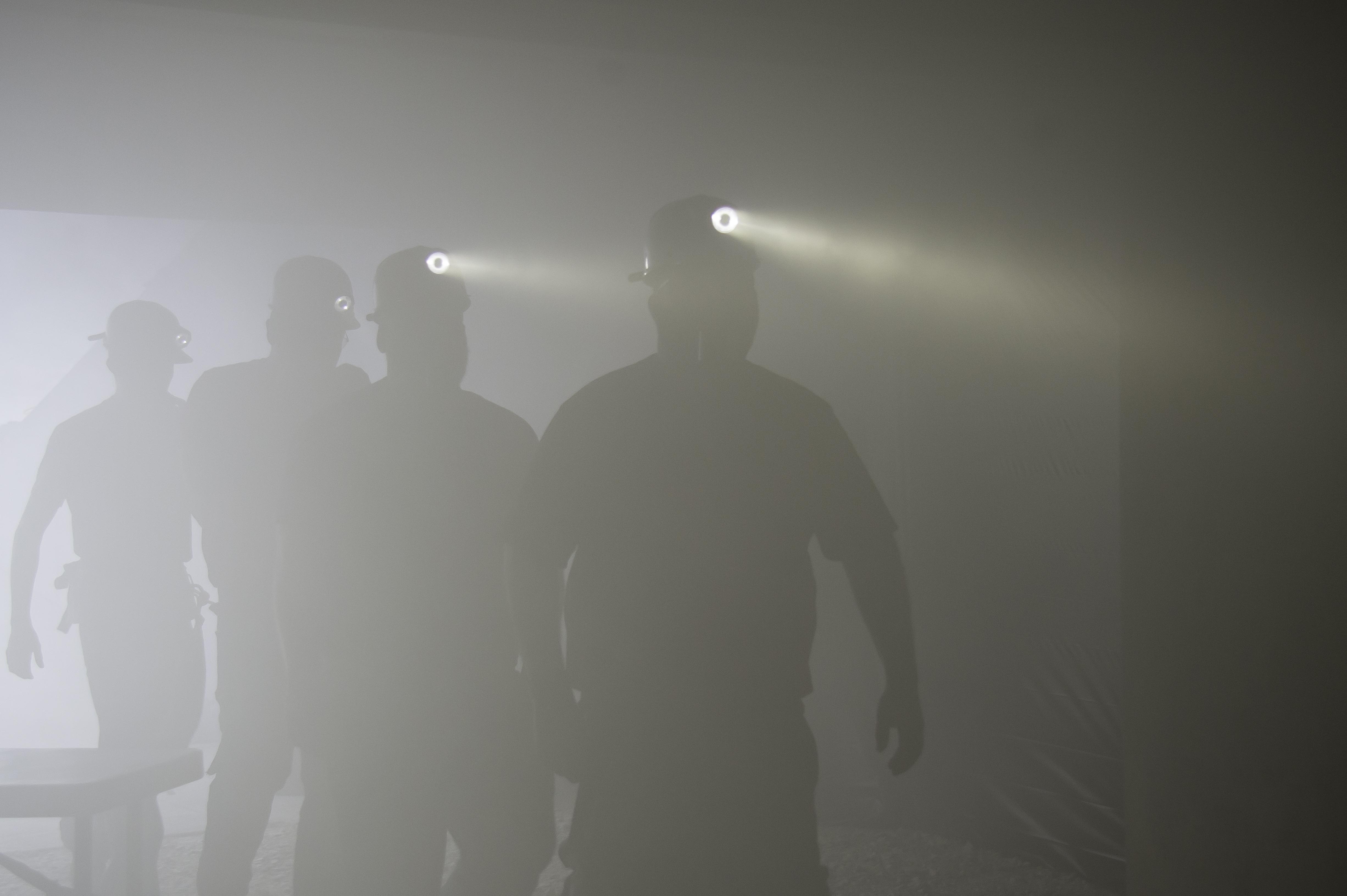 A group of miners in a dark area with their lights on