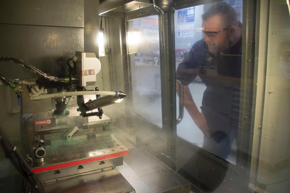 A technology professor examining his project from behind glass doors